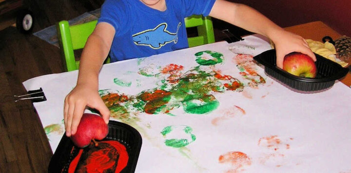 Child making art with apple stamping 