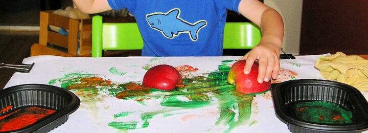 Child stamping apples in paint on paper