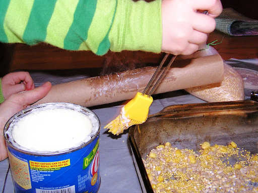Child using pastry brush to spread fat on paper roll