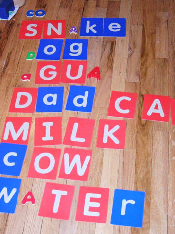 Children's letter cards spelling words on wood floor.