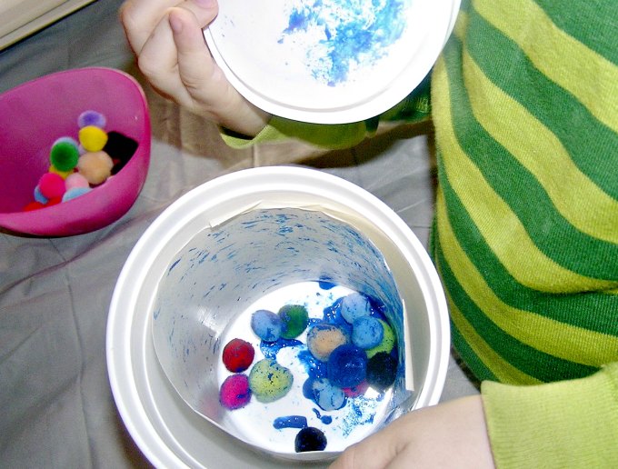 Pom poms in container with paper and paint