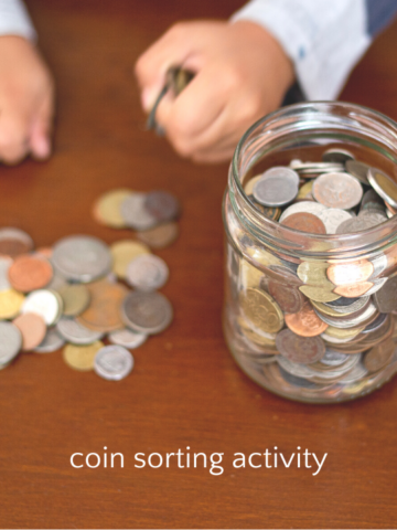 child's hands grabbing coins off table with jar of coins