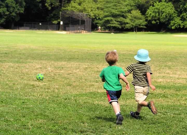 Two boys running after soccer ball