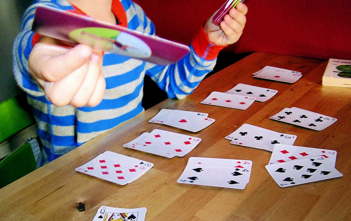 Child holding out playing card while playing go fish