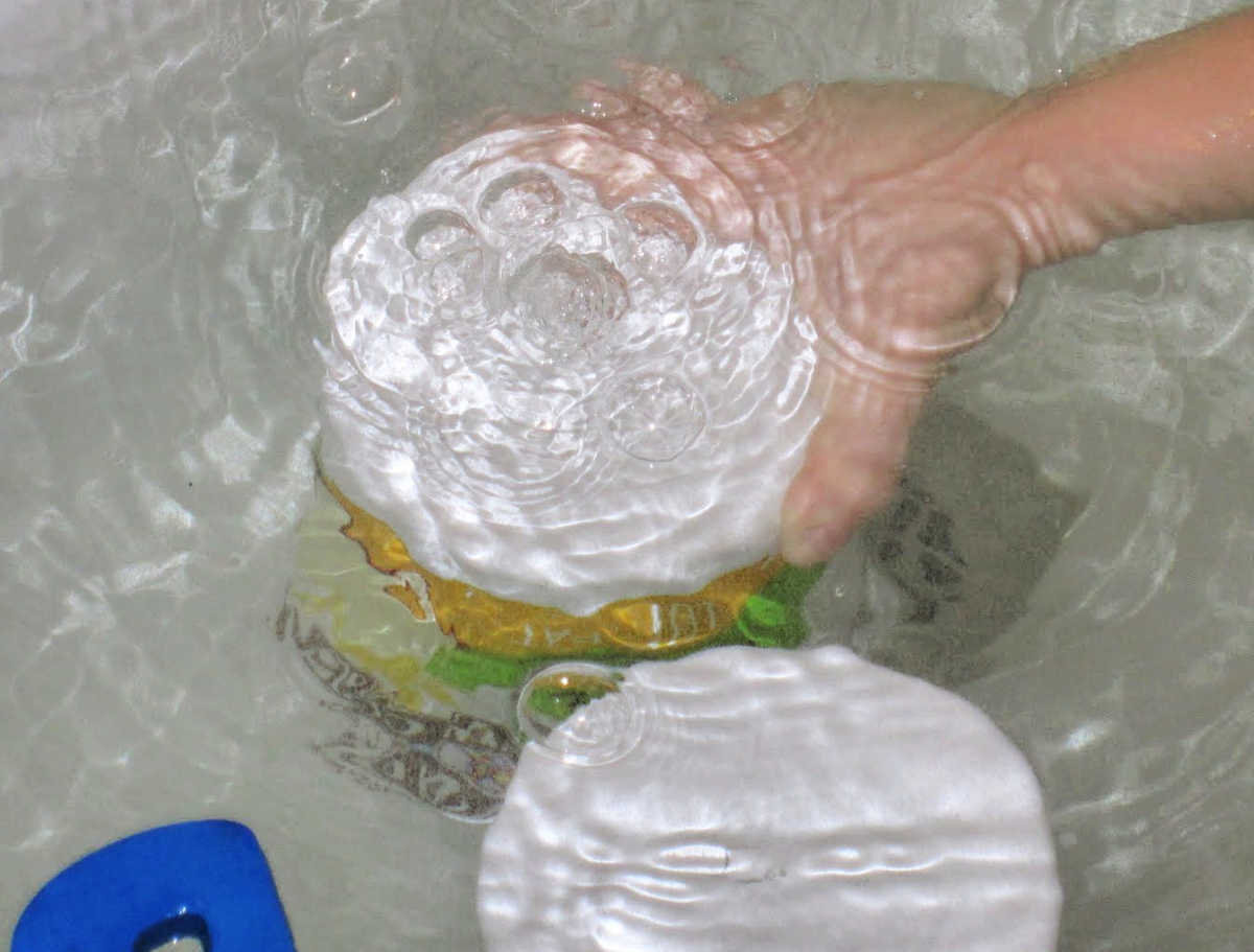 child using plastic container in both water to learn how bubbles form
