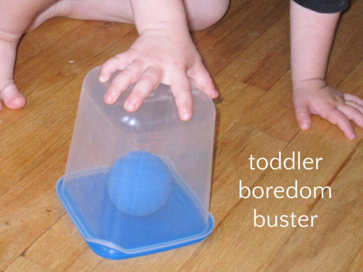Toddler hand holding clear container with blue ball inside