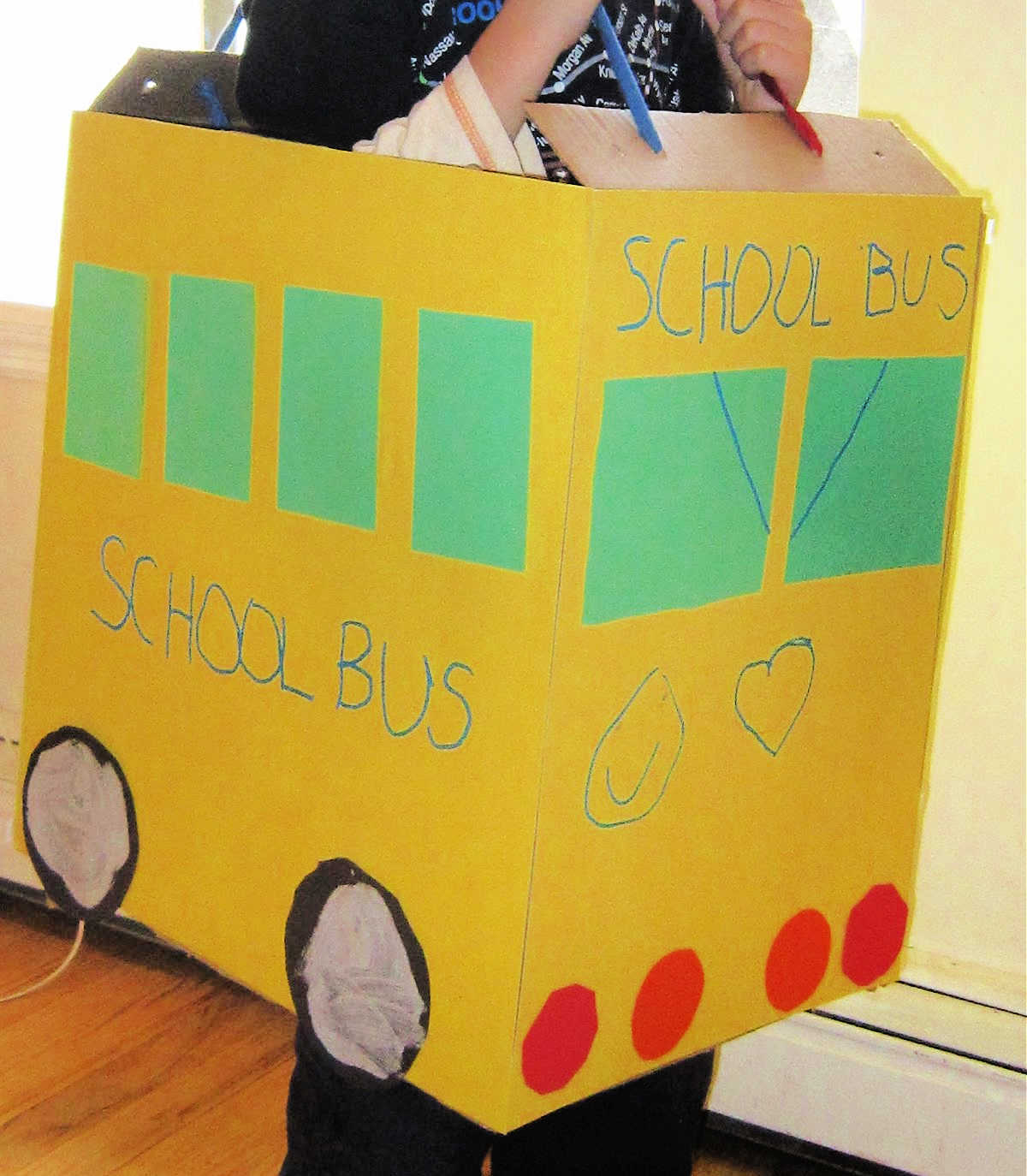 Side view of child in homemade school bus costume made from cardboard box covered in yellow paper