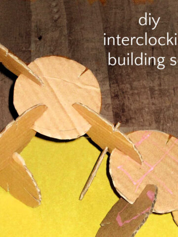 Small cardboard discs interlocking by way of small slots cut into their sides. Group of interlocking discs resting on yellow paper with text overlay, "diy interlocking building set".