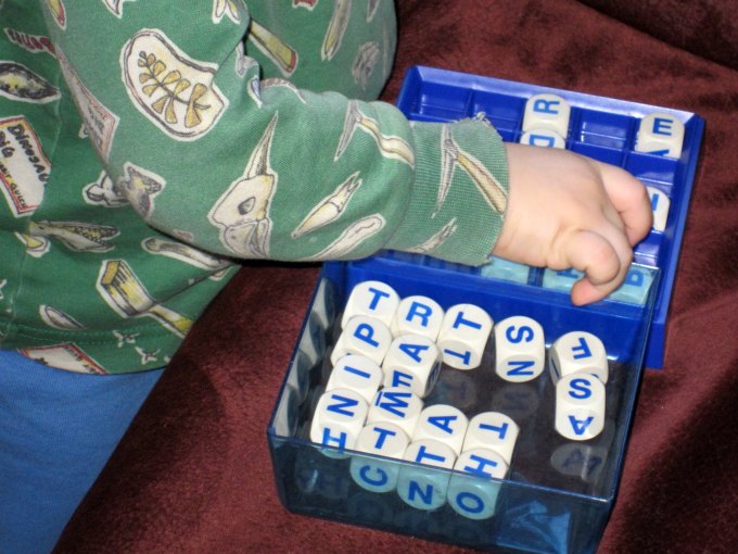 toddler playing with boggle game pieces