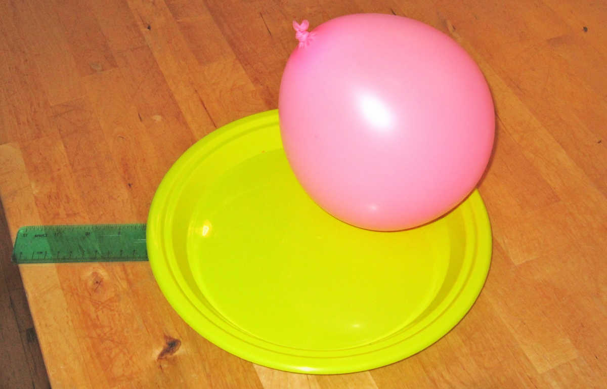 Pink balloon resting on paddle made from plastic plate