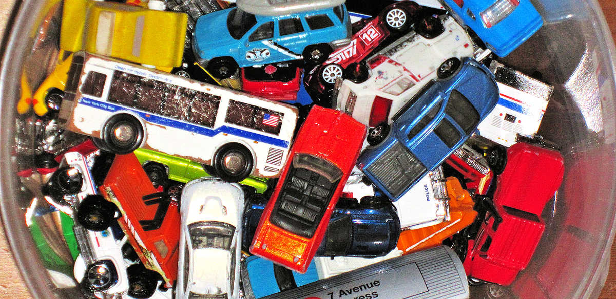 Pile of battered toy vehicles in a plastic bucket