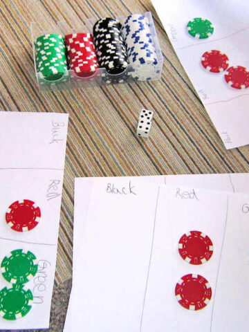 Paper, math chips, dice set out on floor for 5s and 10s math game