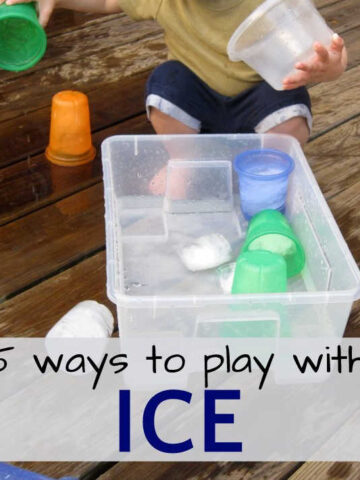Child playing with ice cubes and cup in bucket of water