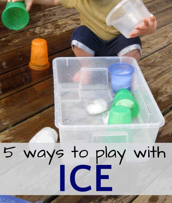 Child playing with ice cubes and cup in bucket of water