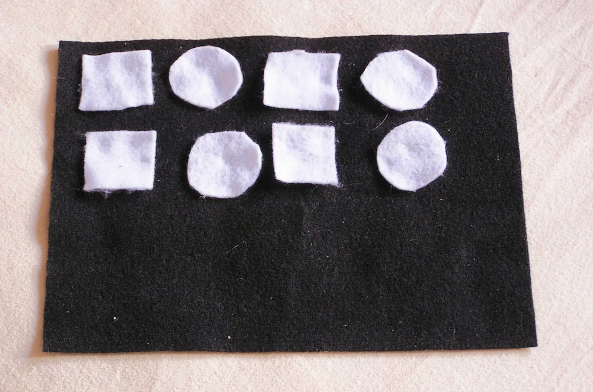 White square and circle felt shapes on black background laid out in square-circle-square-circle pattern.