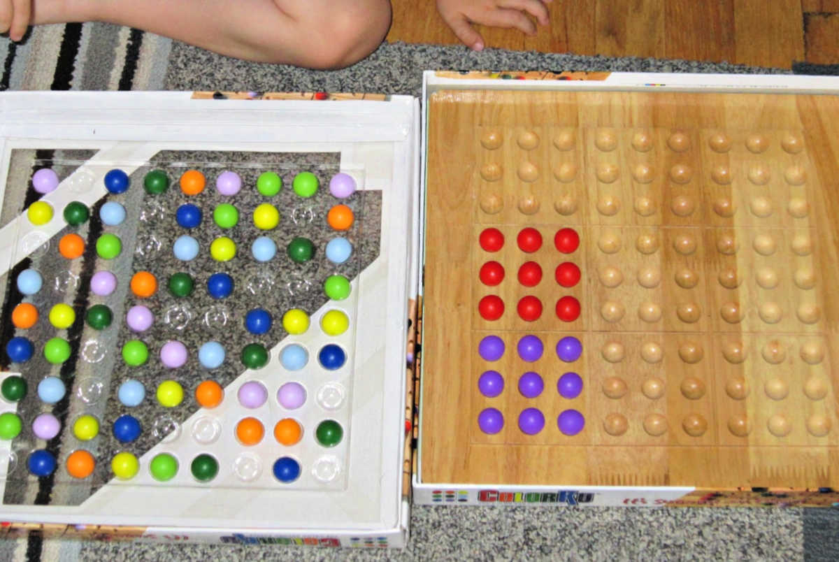 child playing with Colorku game board and colorful wooden marbles