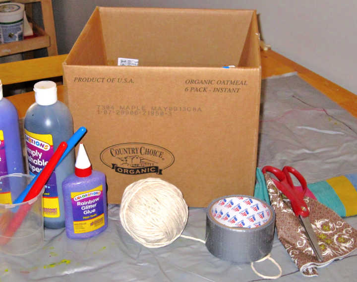 Cardboard box, string, tape, paint and supplies for a diy puppet theater