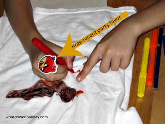 child drawing on tee shirt with fabric pens
