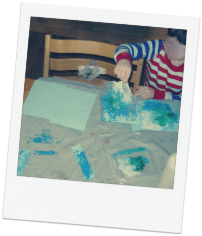 Child miking prints with bubble wrap and blue paint.