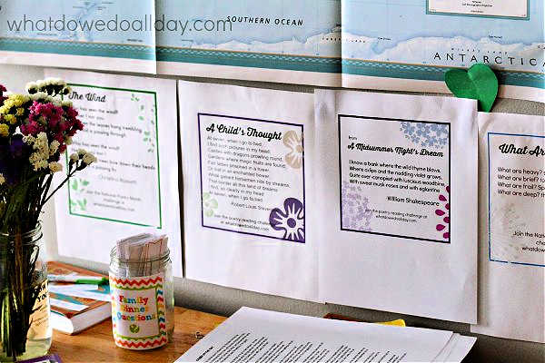 Print out of poems hanging on wall under a map and above a table.