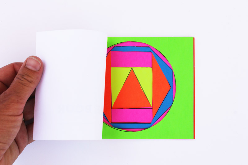 Hand holding shapes book made with bright paper.