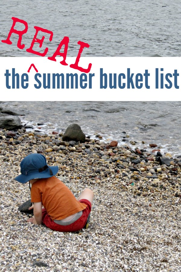 Child sitting on rocky beach near water.