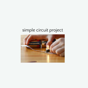Hands holding batteries together to create circuit to illuminate small light bulb