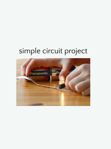 Hands holding batteries together to create circuit to illuminate small light bulb