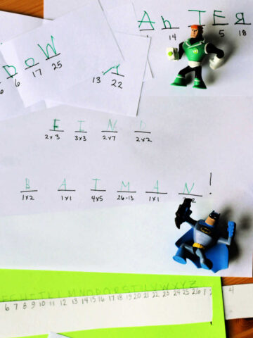 Two superhero figure toys on top of decoded secret message.