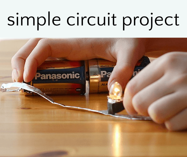 Hands holding batteries together to create circuit to illuminate small light bulb