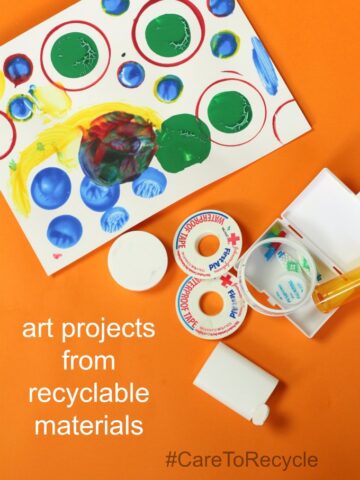 Assortment of recycled materials and containers next to art work consisting of multicolored dots.