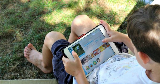 Child outside reading on a tablet.