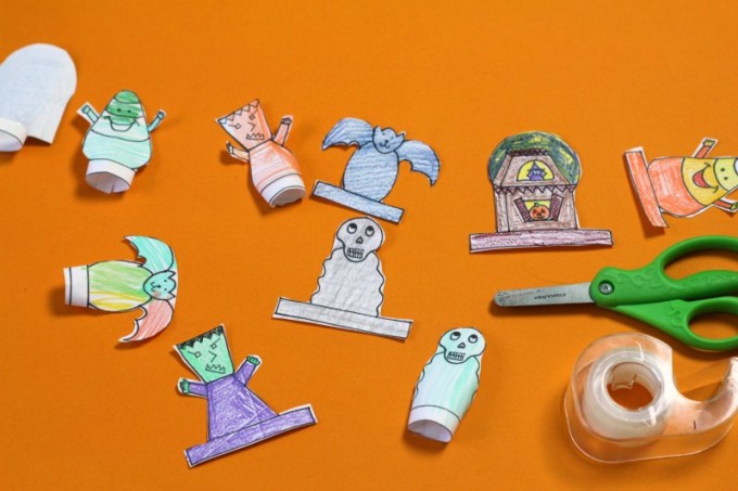 Halloween finger puppets in several stages of completion with scissors and tape dispenser