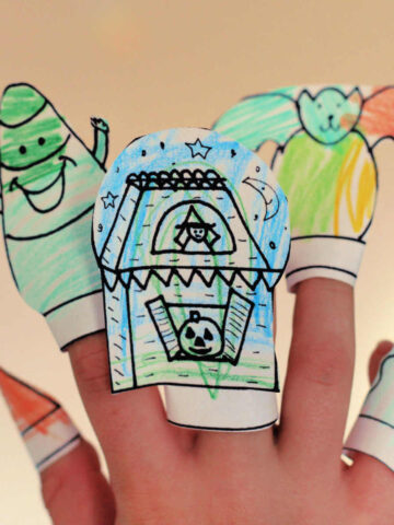 Child's hand wearing five homemade Halloween finger puppets.
