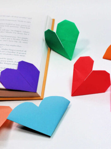 Origami heart bookmarks next to open book.