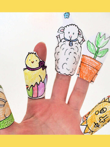 Hand wearing five paper finger puppets: bunny, chick in egg, lamb, flower pot and sun.