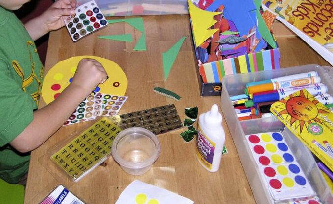 Craft supplies on table with child working on moon art