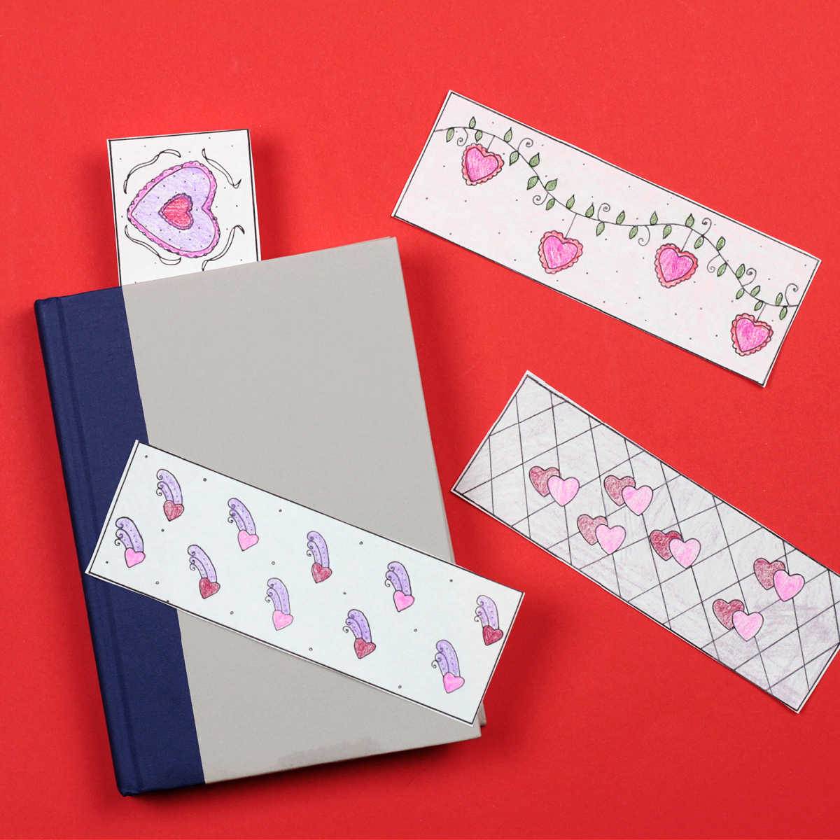 four colored valentine bookmarks on red background with one sticking out of grey book