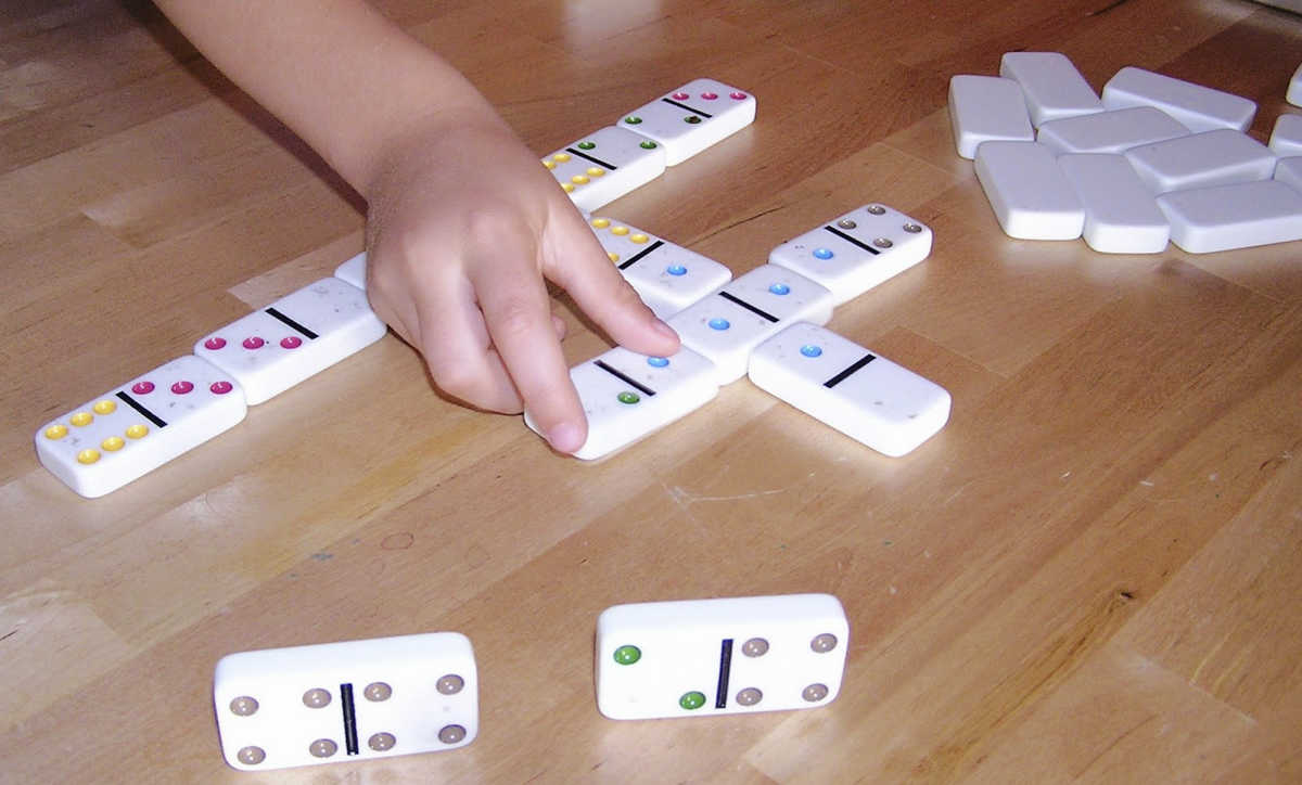 Child's hand reaching for dominoes.