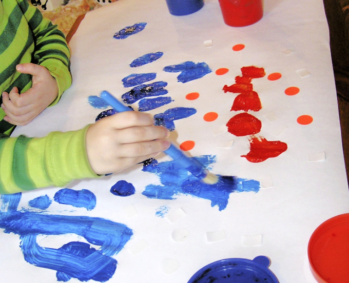 Child painting with blue and orange paint