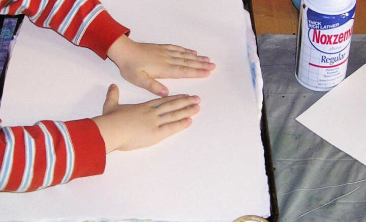 Hands pressing paper onto shaving cream