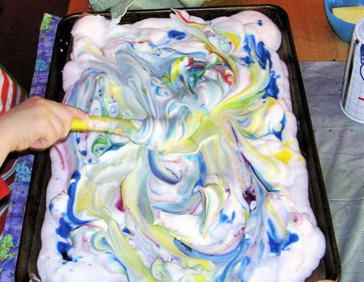 Swirling watercolors into shaving cream with plastic knife