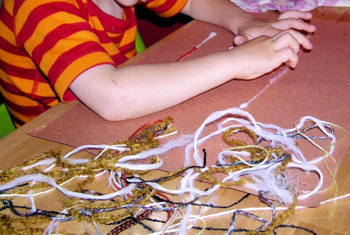 Child applying string to brown paper for fine motor craft project