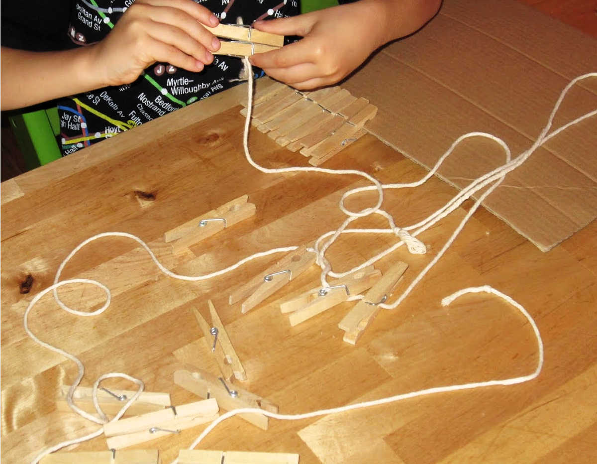 Child clipping clothespins to a string