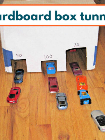 Three entrance tunnel made out of a cardboard box with lines of toy cars waiting to go through.