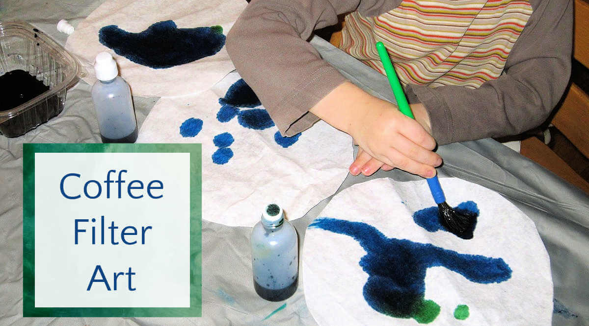 Child applying blue watercolor to large coffee filter