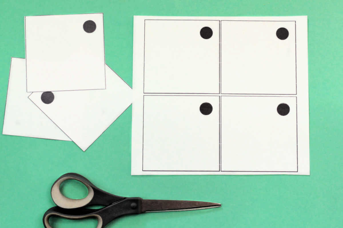Paper with four squares with dot in the corner, plus scissors