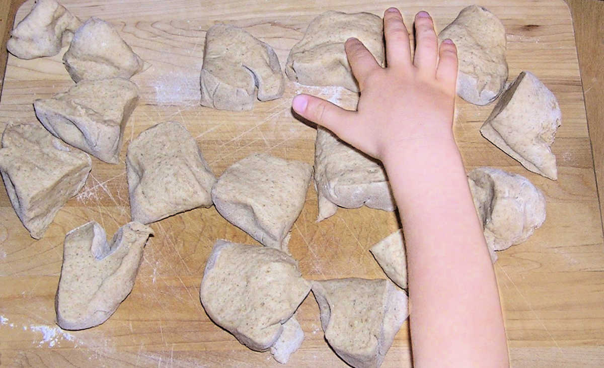 Child counting 16 balls of pretzel dough on cutting board
