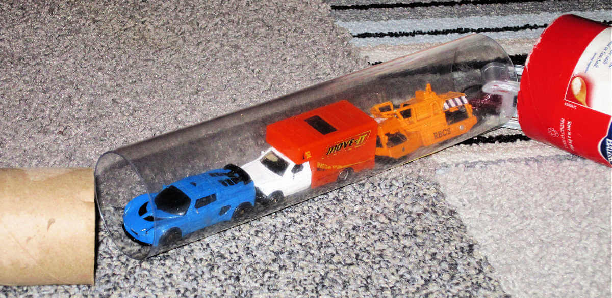 toy vehicles lined up in clear tube on carpet