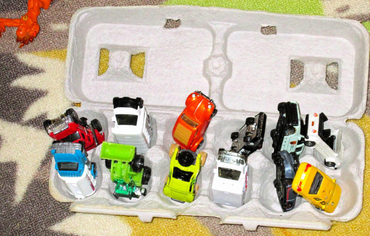 toy cars in sections of cardboard egg carton